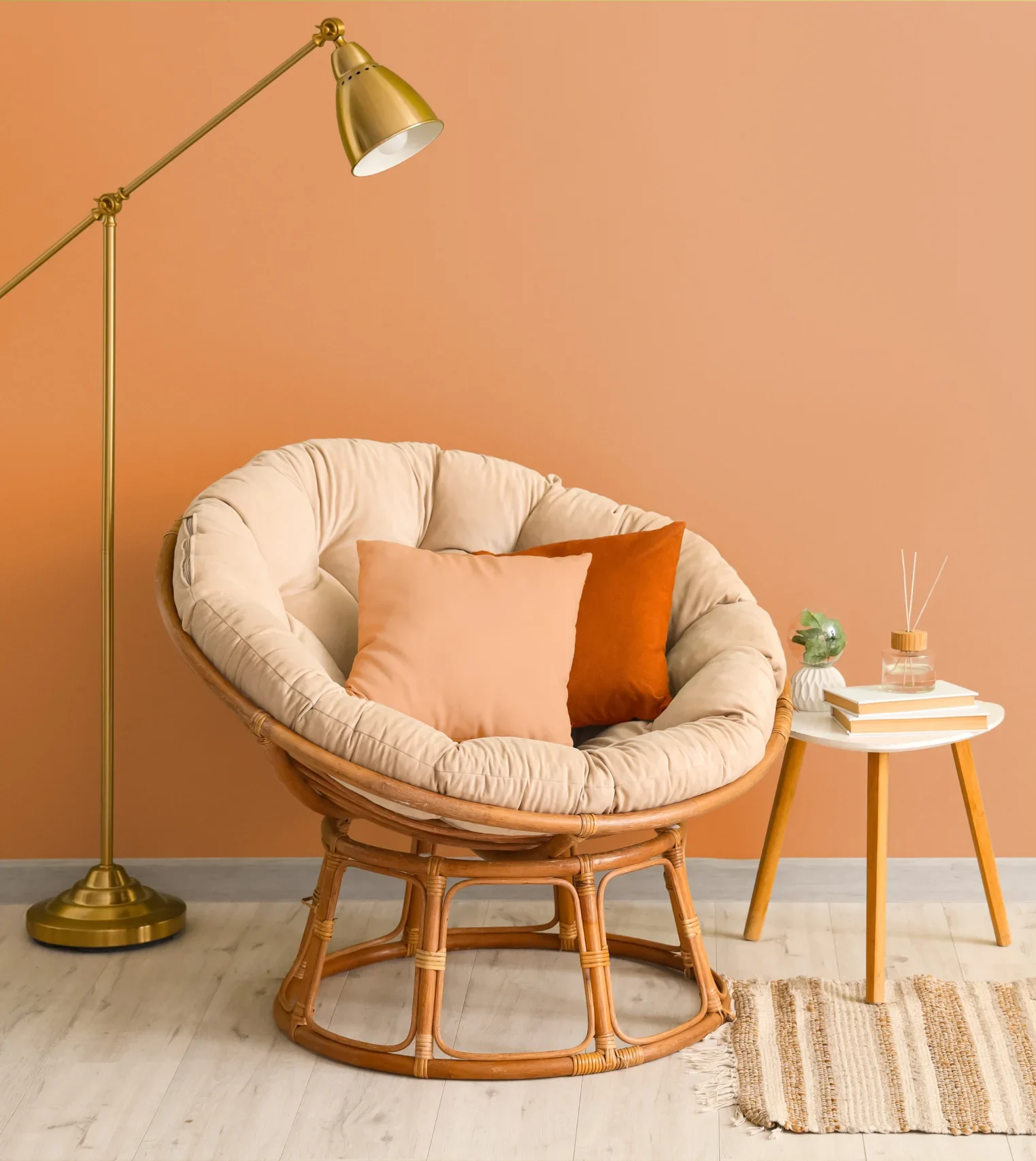Peachy chair with cushions. Lamp and desk behind the chair.